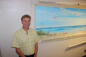 Local artist Patrick Richard with his artwork which he donated to honor Metrocom